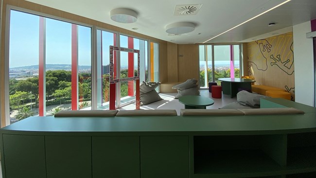 A room with multicolored furniture looking out on a verdant landscape
