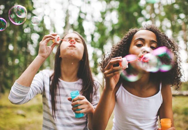 Two children blow bubbles outdoors